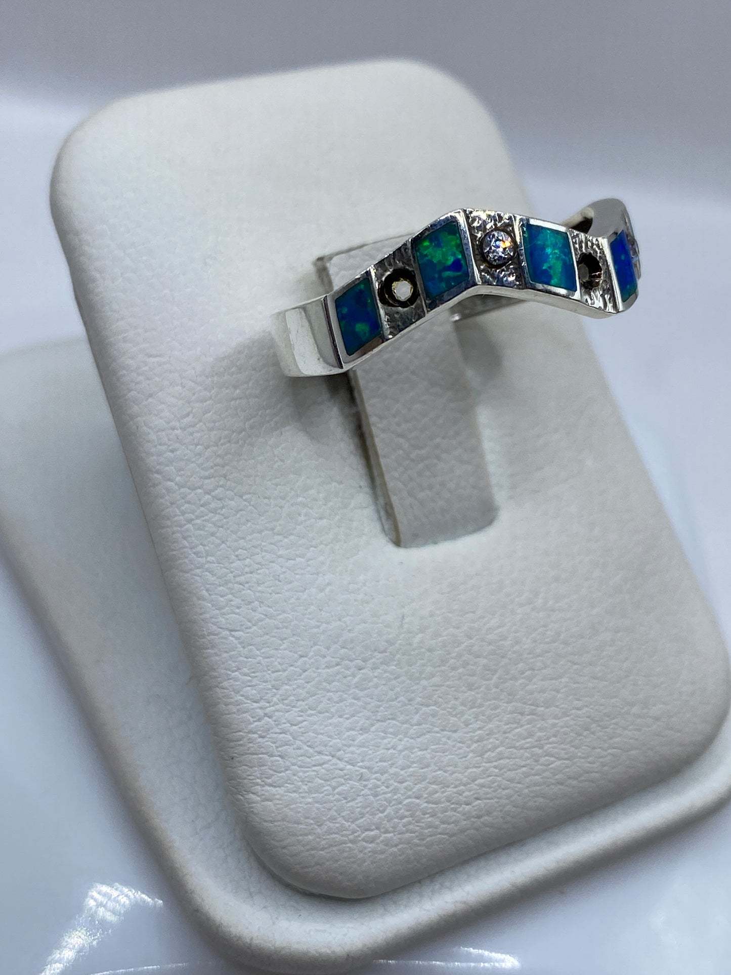 Vista lateral del anillo minimalista en plata .950 mostrando el engaste del ópalo azul