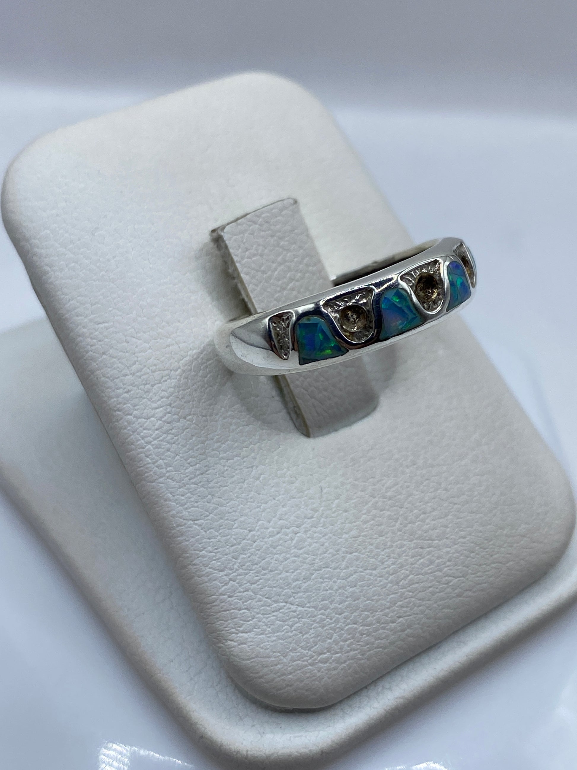 Detalle lateral del anillo con ópalo natural mostrando juego de colores azul y verde