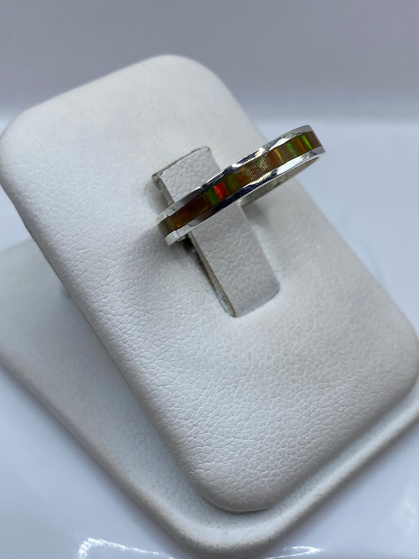 Vista lateral del anillo minimalista en plata pura .950 mostrando el ópalo de fuego