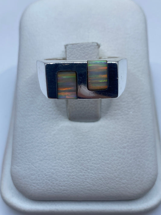 Anillo de plata con ópalo de fuego en dos recuadros mostrando juego de colores verde, rojo y naranja