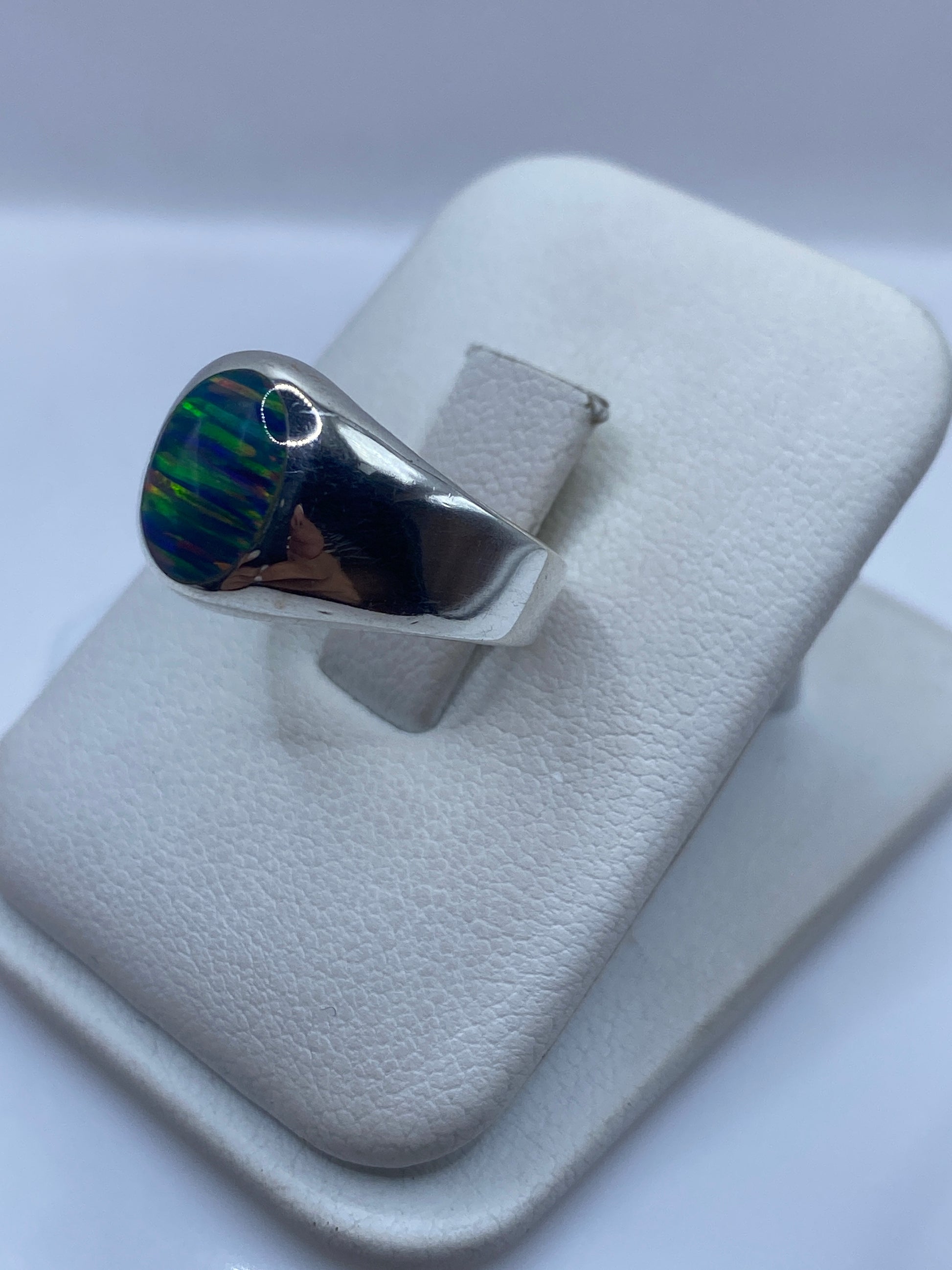 Vista lateral del anillo de plata con ópalo de fuego mostrando fuegos naranja y verde