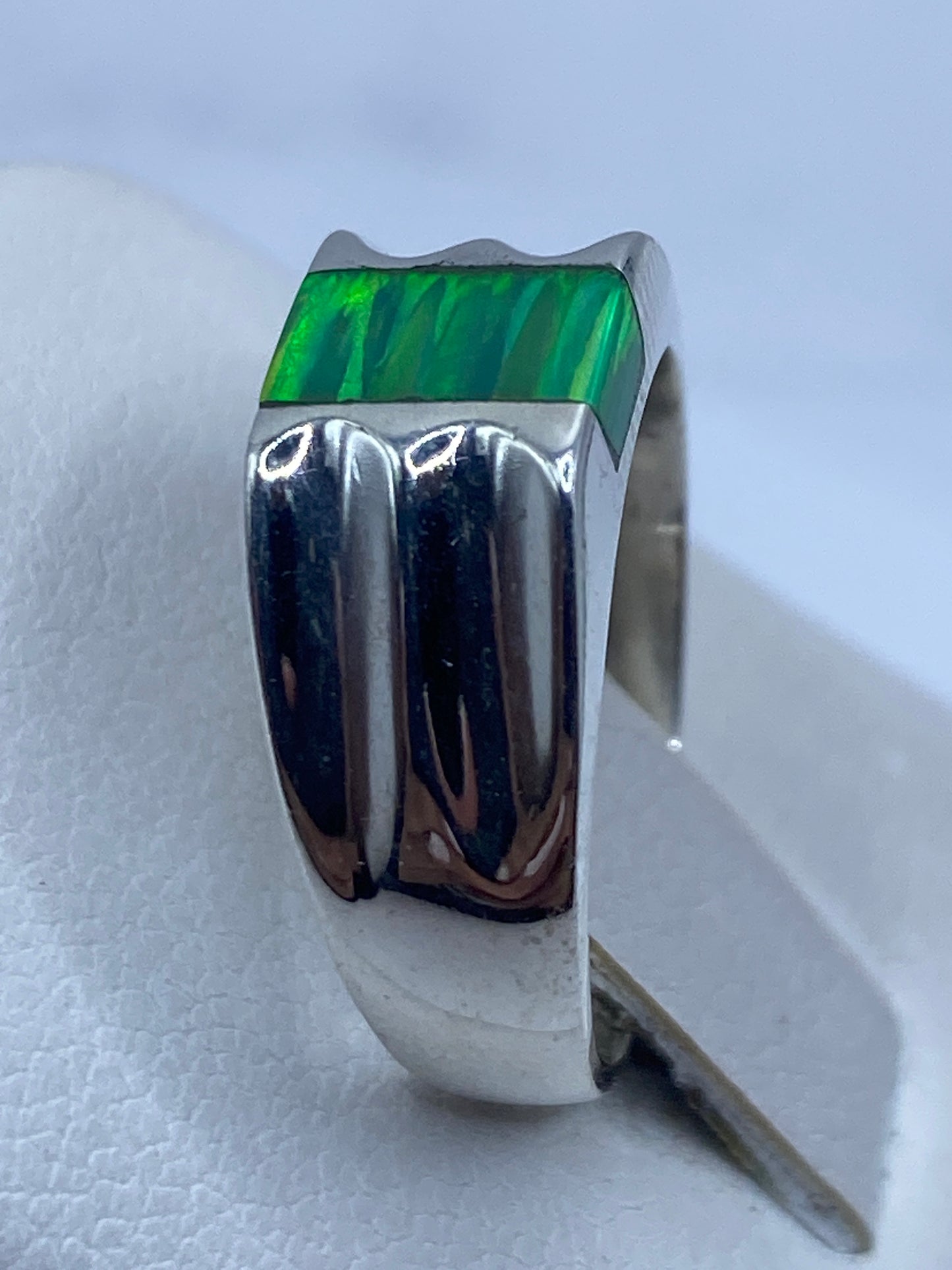 Anillo ópalo de fuego en dedo, mostrando los tonos verdes y dorados de la piedra natural