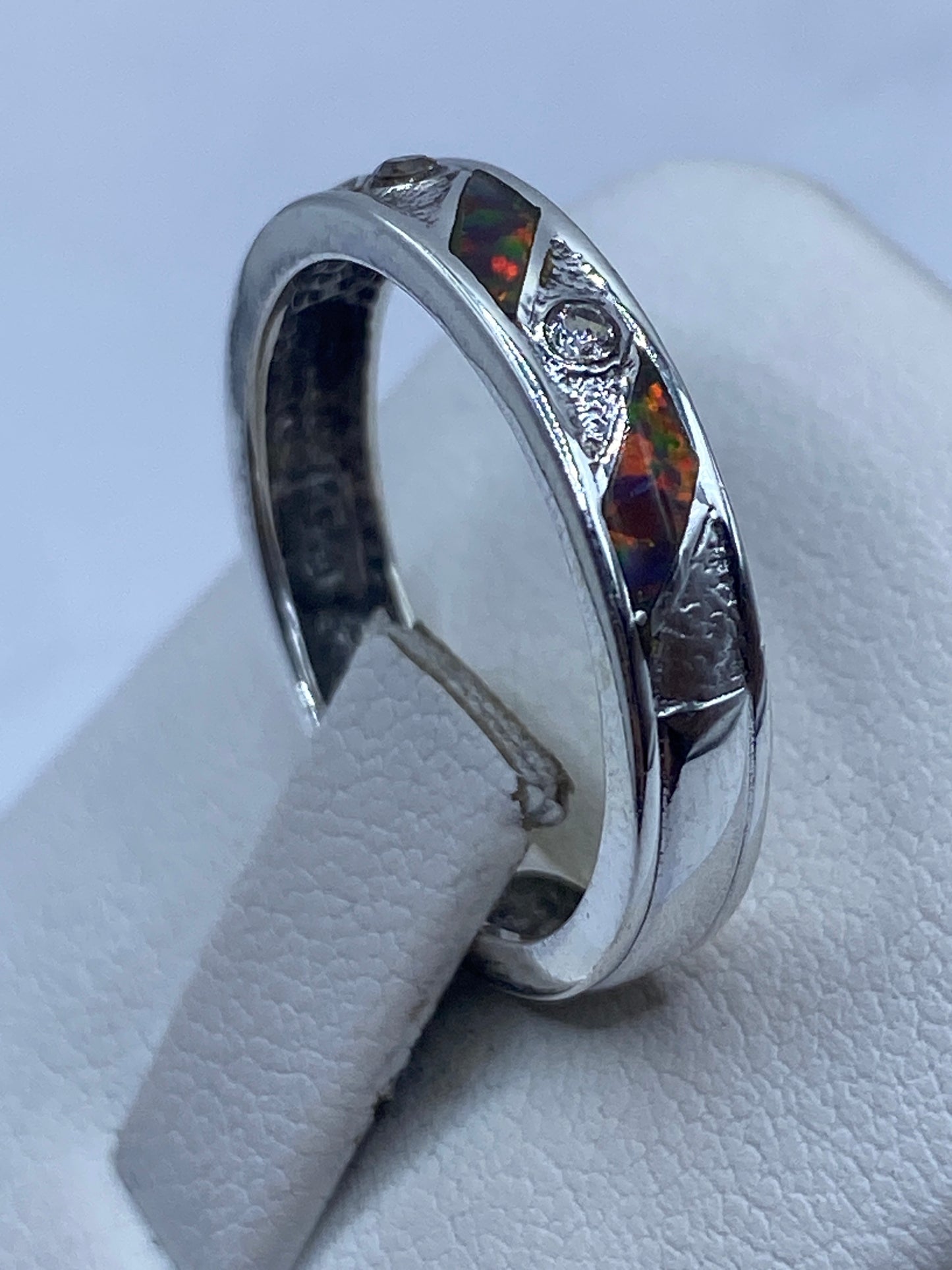 Vista lateral del anillo moderno en plata pulida, ópalo visible desde el perfil