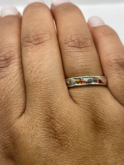 Anillo en dedo de mujer con ópalo de fuego capturando luz natural, colores vivos