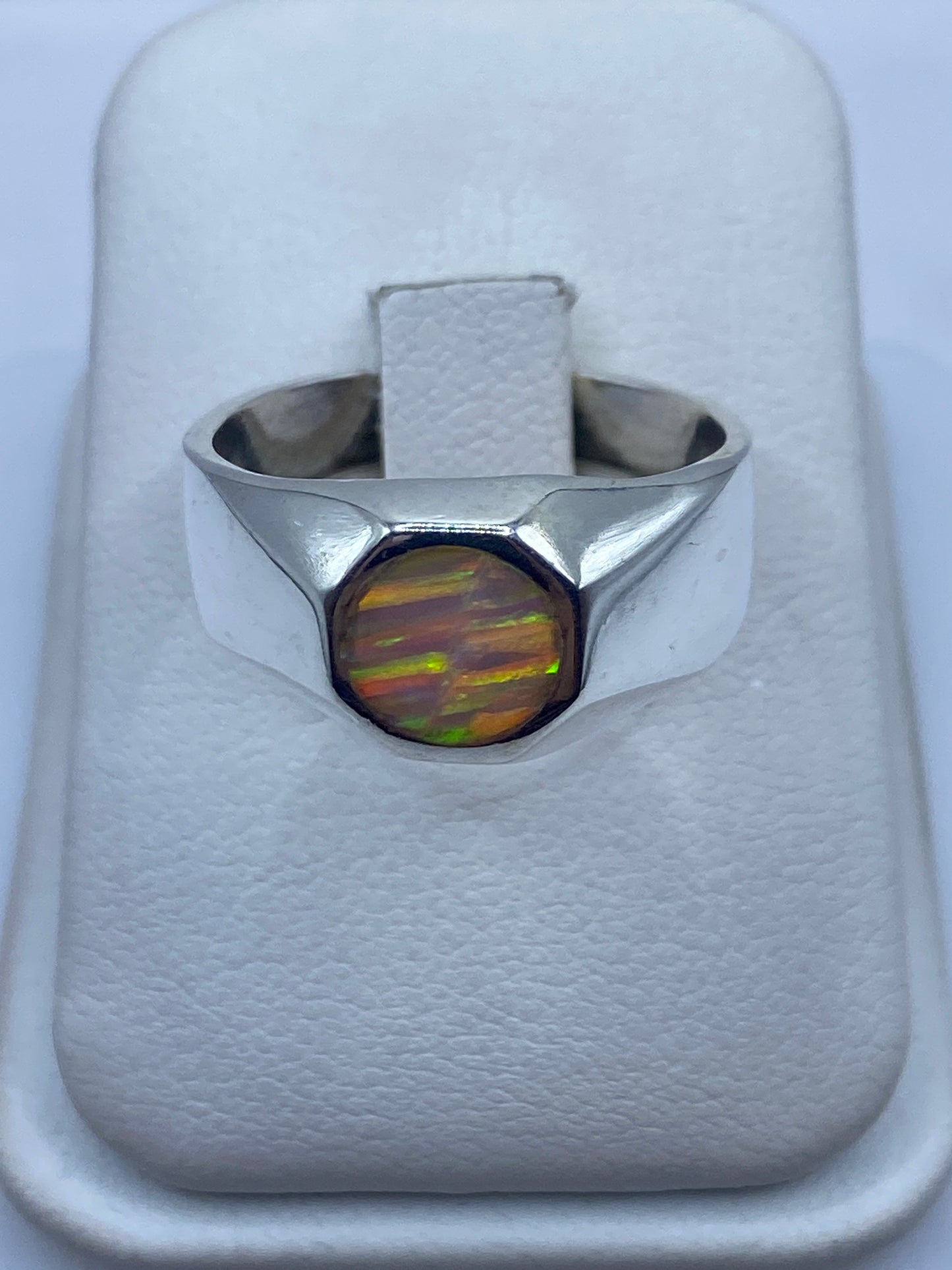 Anillo de plata con ópalo de fuego multicolor mostrando destellos rojo y naranja