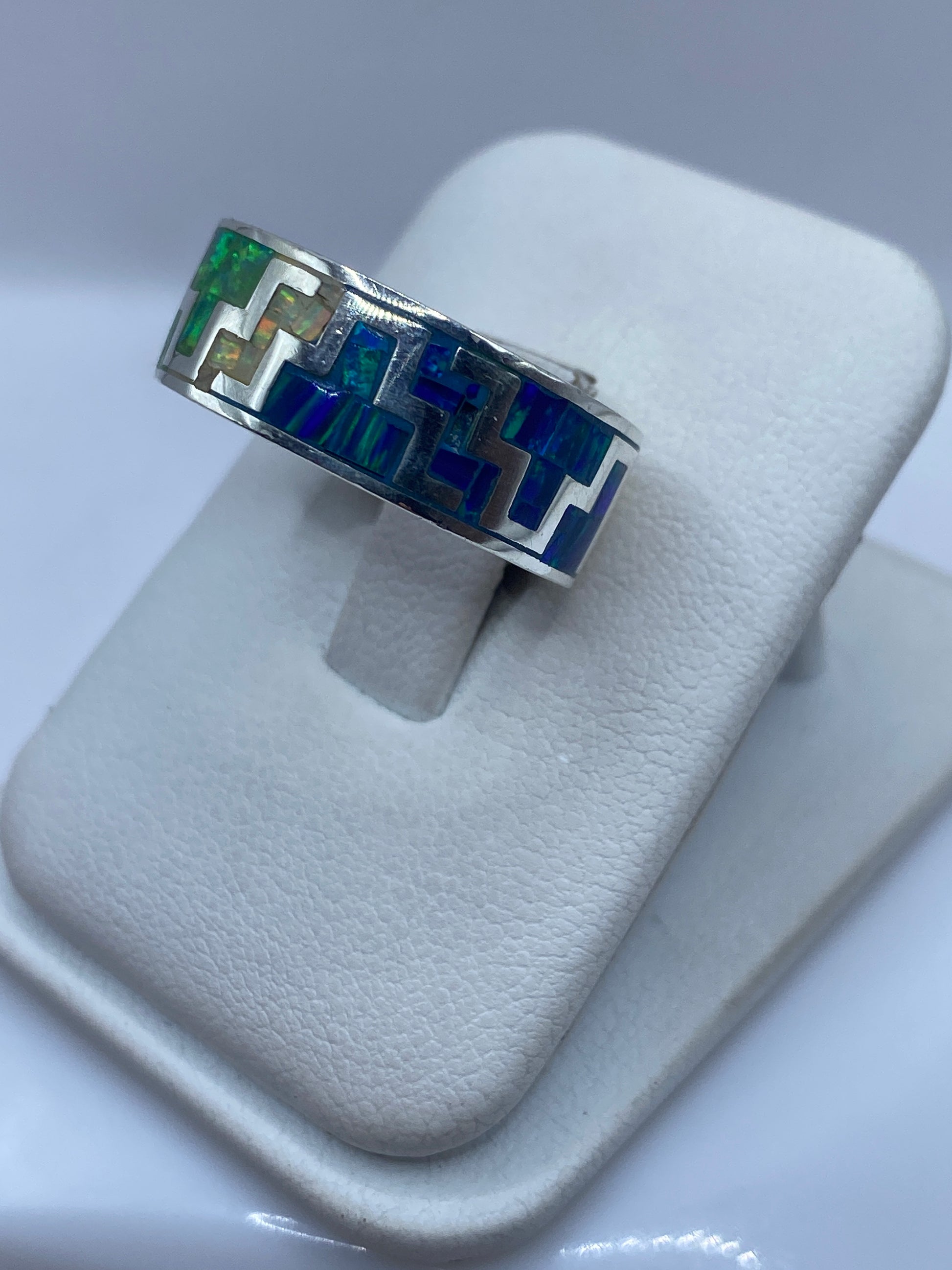 Vista frontal del anillo coctel con juego de colores verde, azul y dorado del ópalo