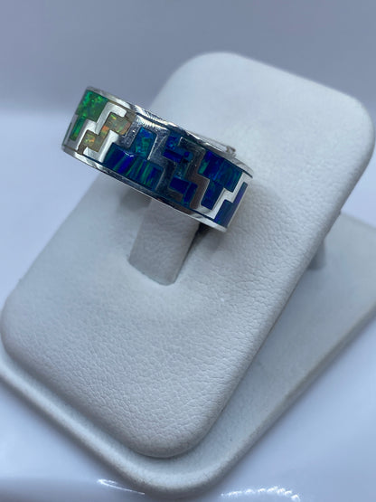 Vista frontal del anillo coctel con juego de colores verde, azul y dorado del ópalo