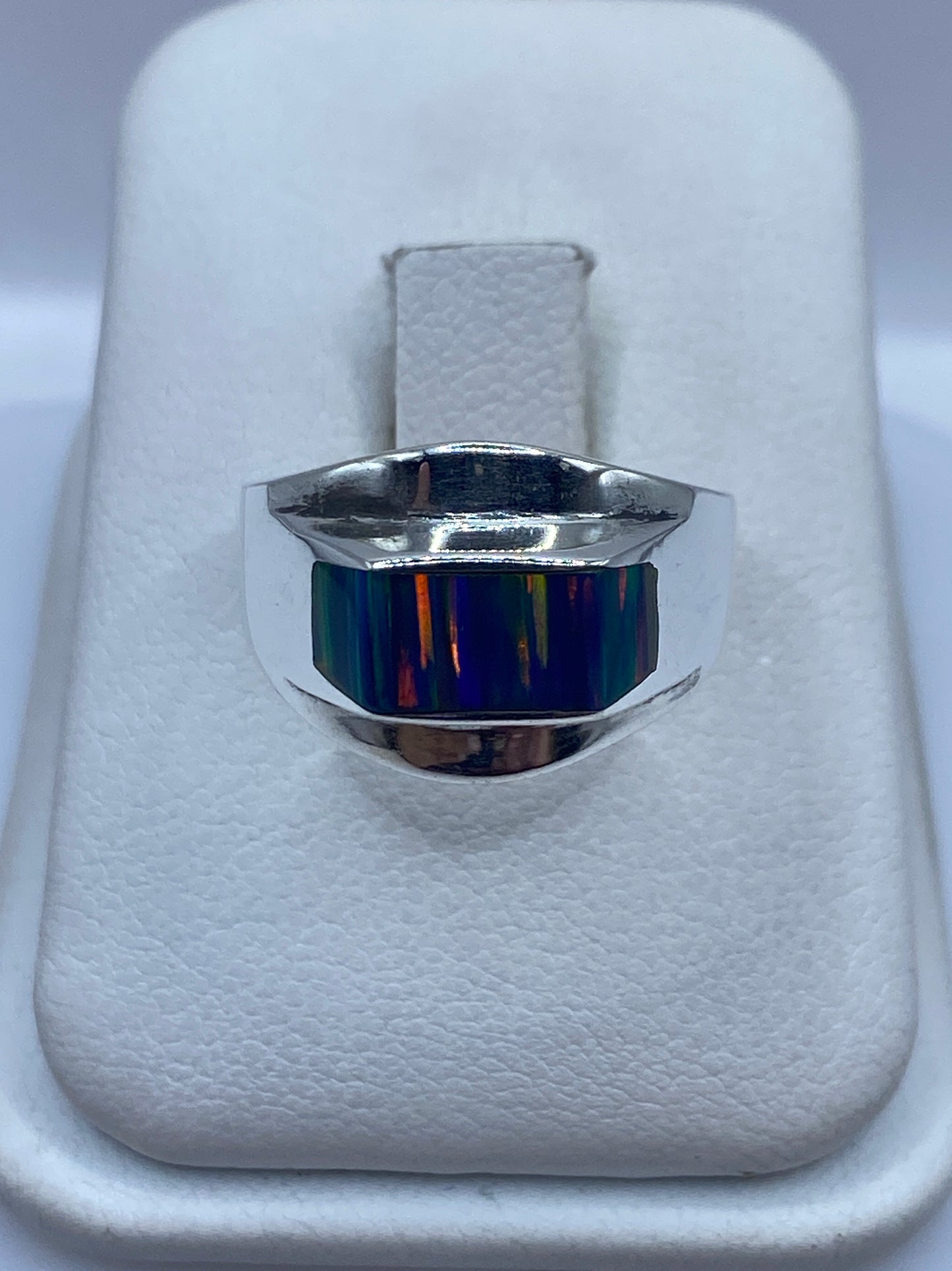 Anillo de plata .950 con ópalo de fuego multicolor sobre almohada blanca, vista frontal
