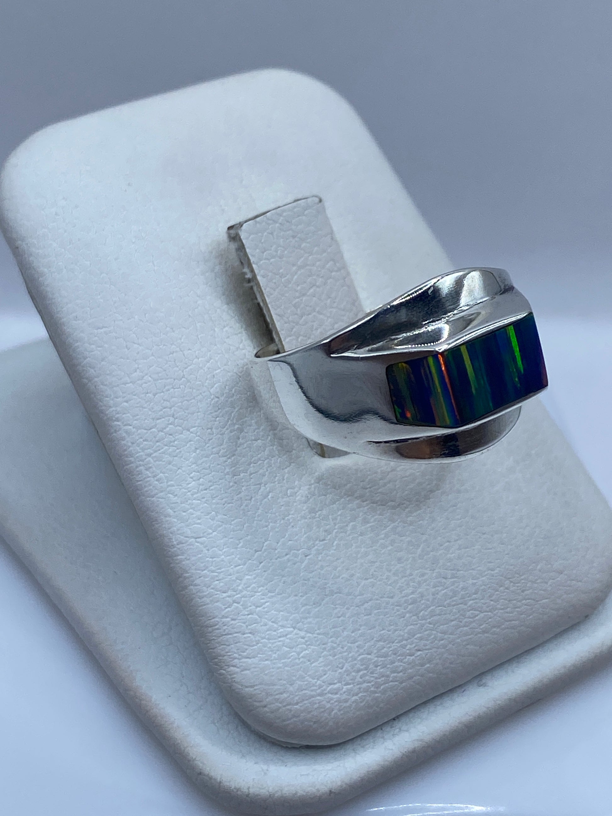 Detalle lateral del anillo mostrando el juego de colores del ópalo: naranjas, azules y verdes