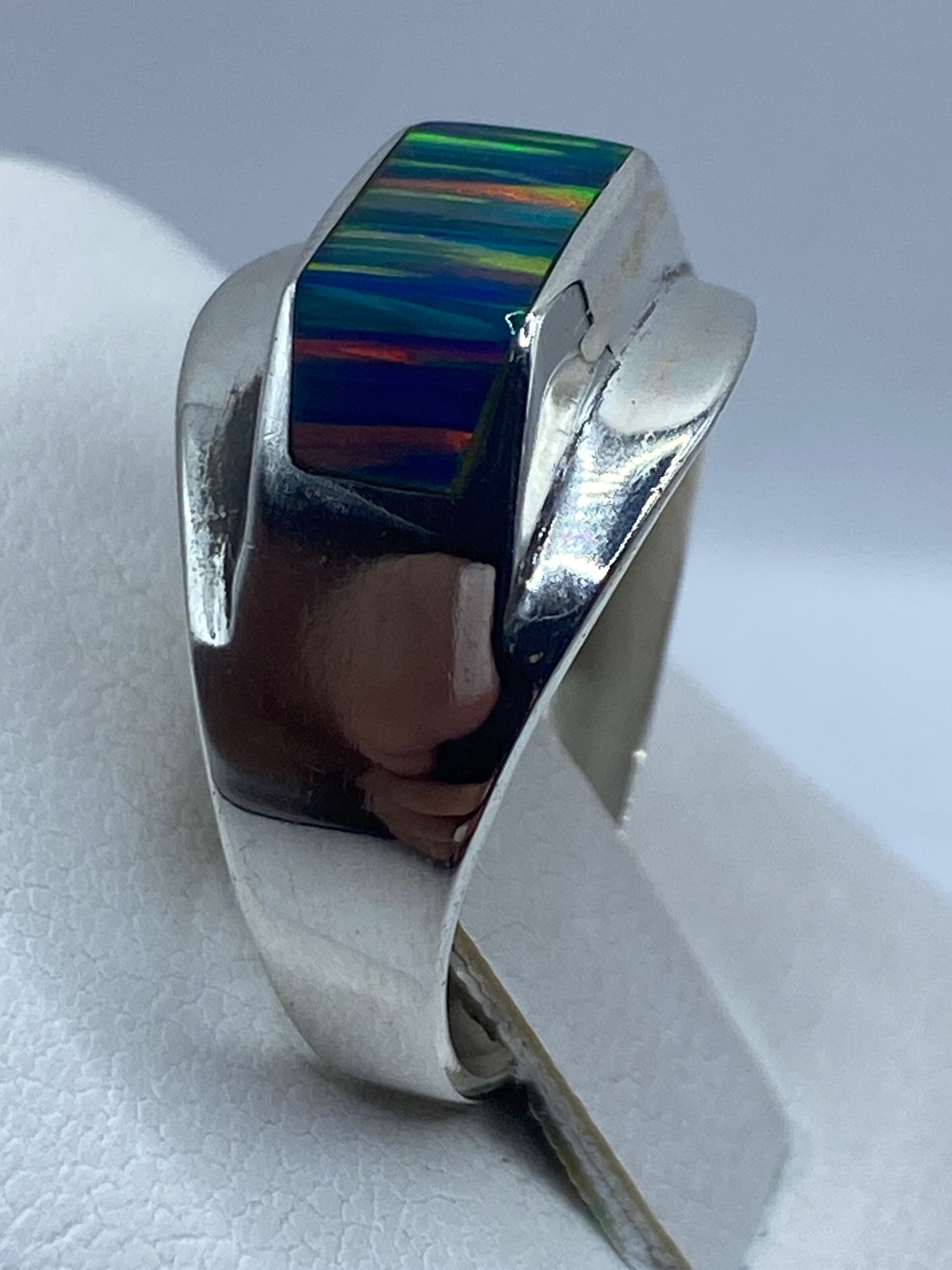 Anillo de ópalo de fuego puesto en dedo, iluminación natural resaltando los tonos