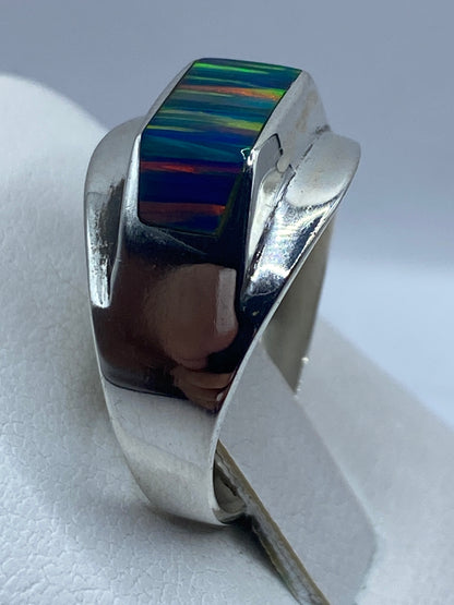 Anillo de ópalo de fuego puesto en dedo, iluminación natural resaltando los tonos