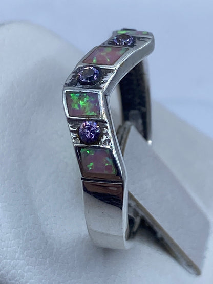 Detalle lateral del anillo en la mano, ópalo de fuego brillando con tonos violeta y rosa