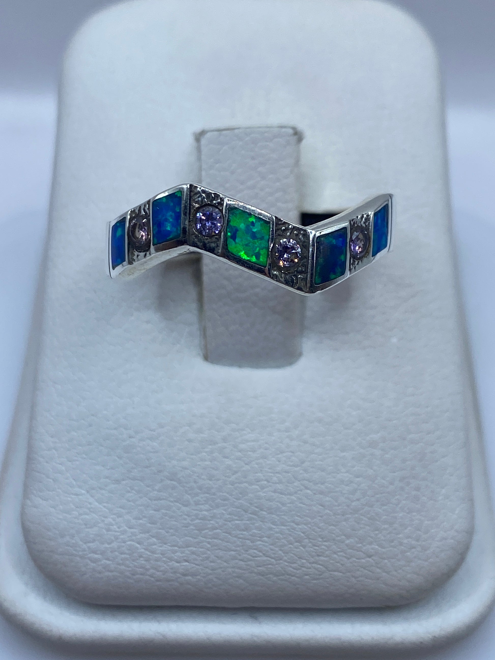 Anillo de plata .950 con ópalo de fuego azul en forma de V sobre dedo de mujer