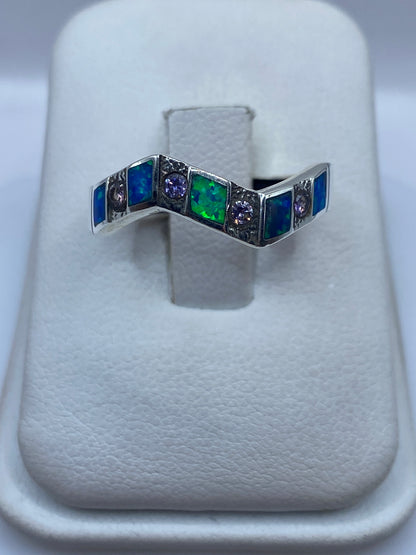 Anillo de plata .950 con ópalo de fuego azul en forma de V sobre dedo de mujer