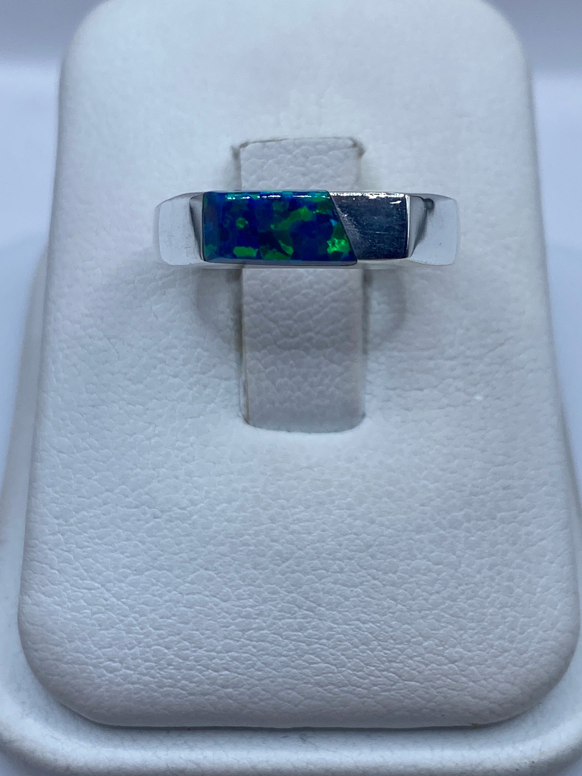 Anillo de plata .950 con ópalo de fuego azul sobre soporte de terciopelo blanco