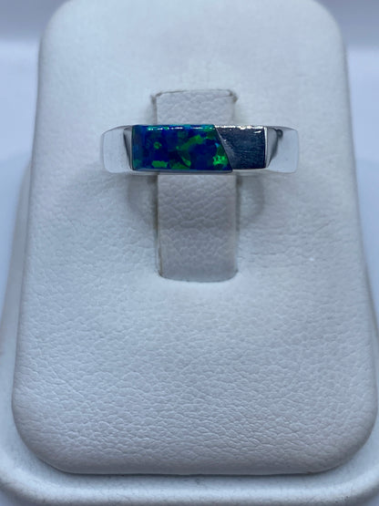 Anillo de plata .950 con ópalo de fuego azul sobre soporte de terciopelo blanco