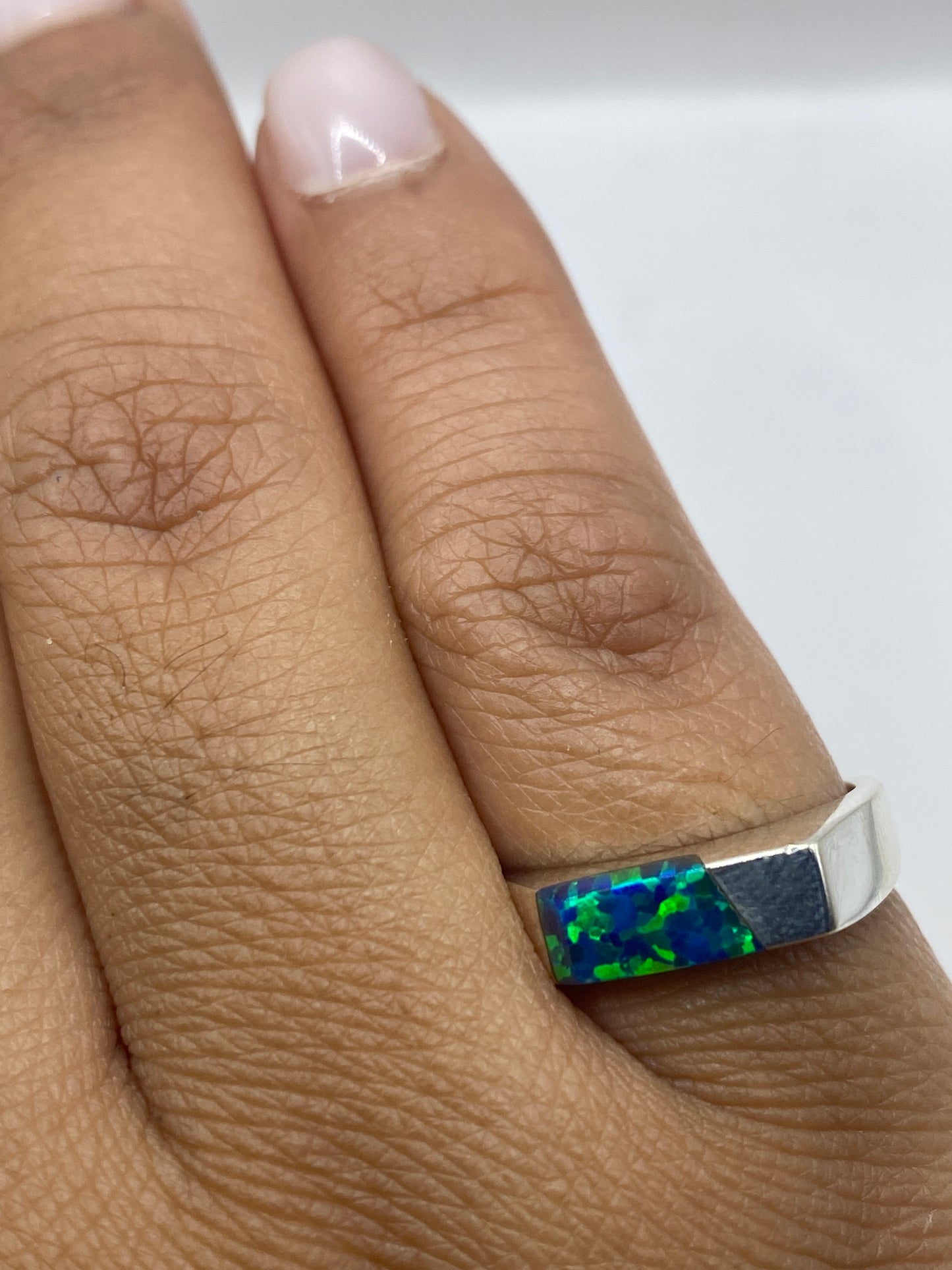 Anillo en dedo mostrando el color azul vibrante del ópalo de fuego natural
