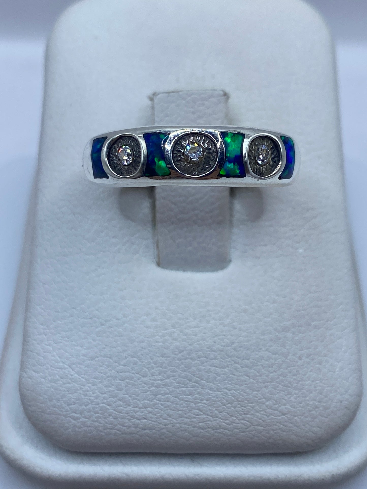 Anillo de plata .950 con ópalo de fuego azul sobre banda minimalista, vista frontal en dedo