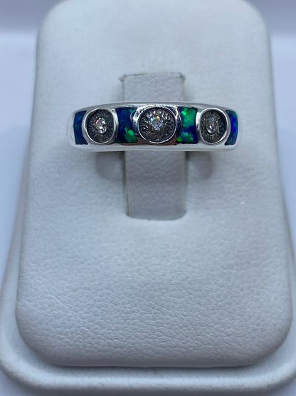 Anillo de plata .950 con ópalo de fuego azul sobre banda minimalista, vista frontal en dedo