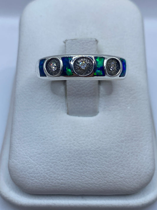 Anillo de plata .950 con ópalo de fuego azul sobre banda minimalista, vista frontal en dedo