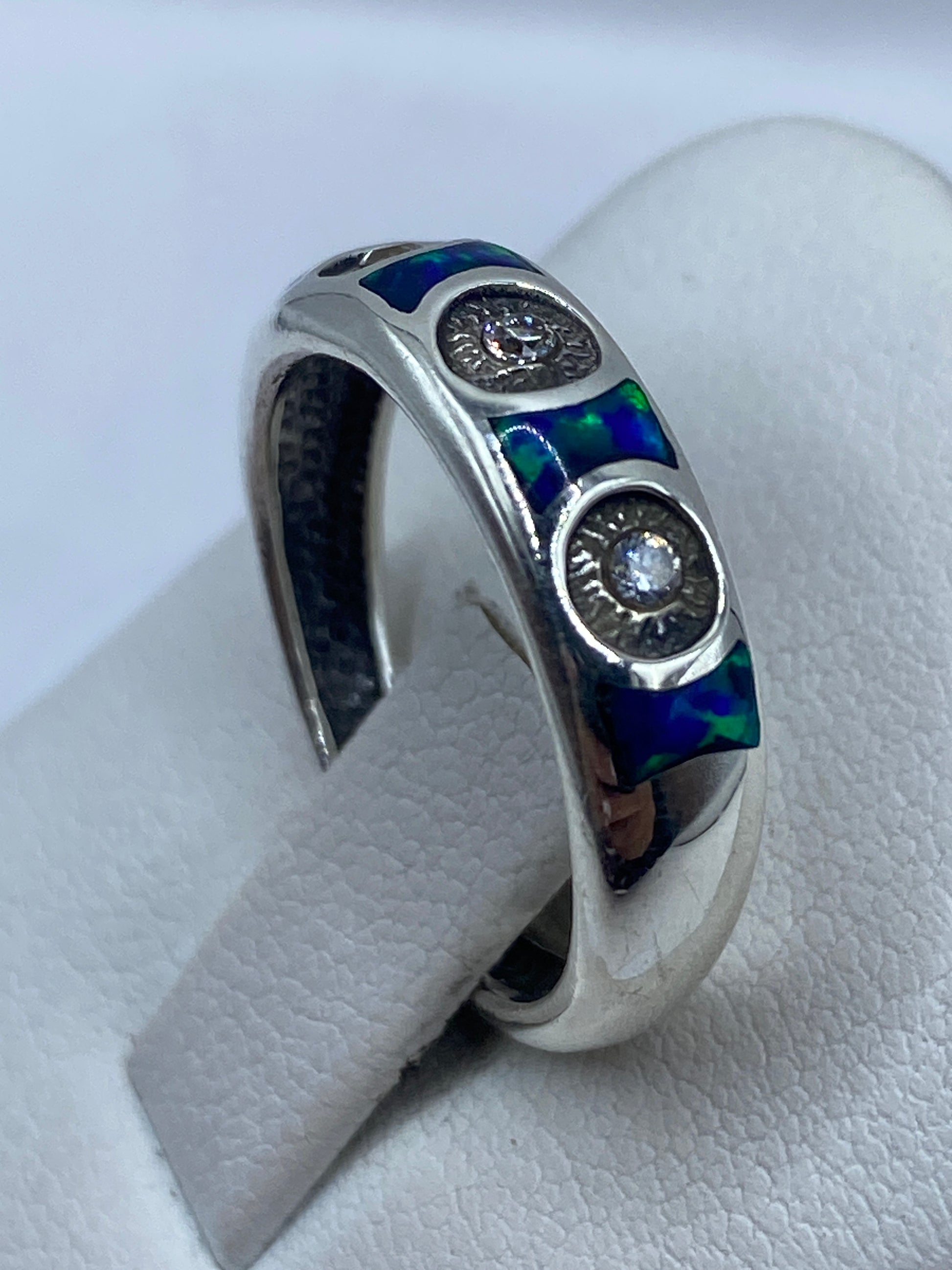 Anillo minimalista de plata .950 visto de perfil sobre dedo, ópalo azul destacado