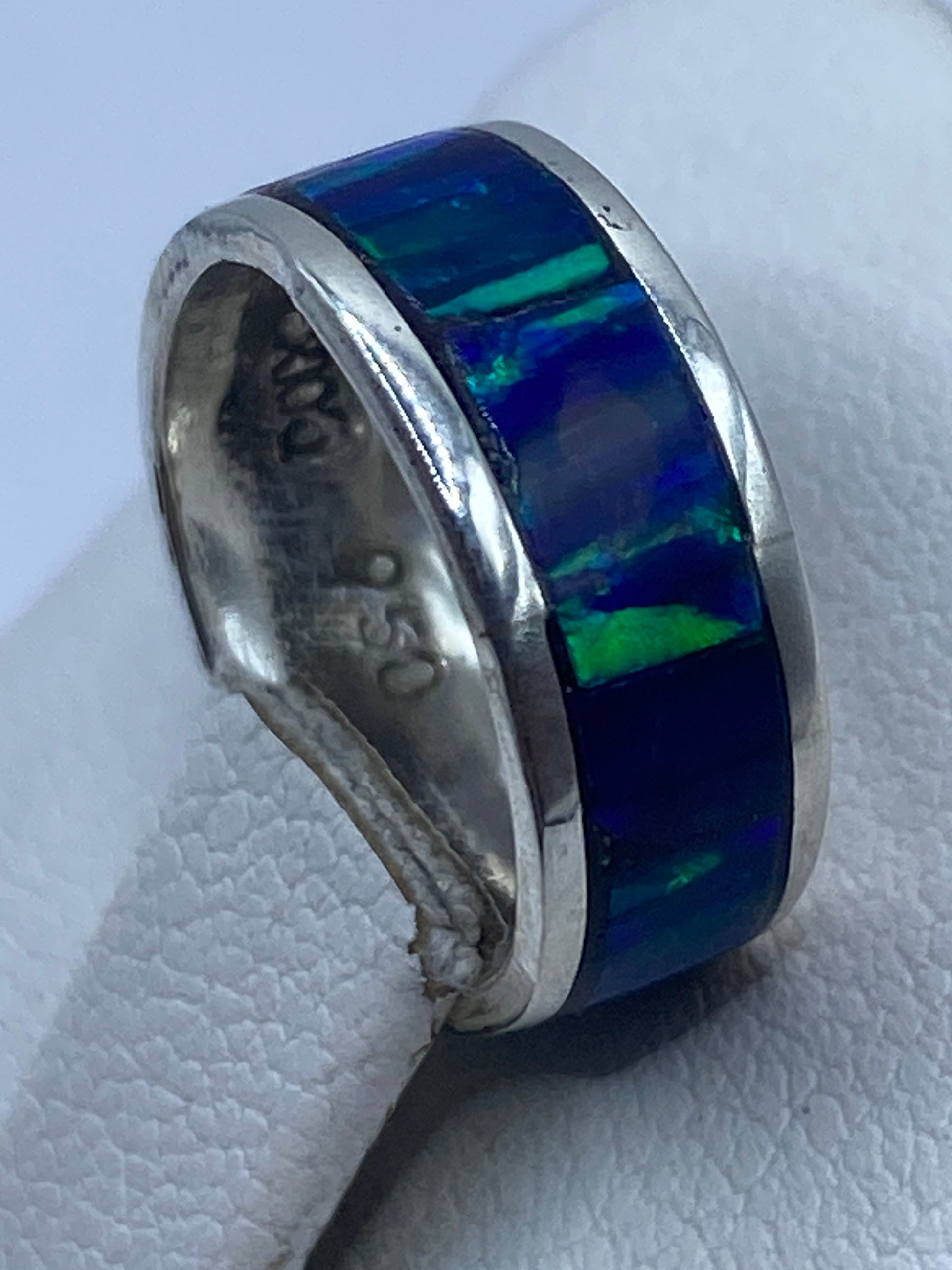 Anillo ópalo azul puesto en dedo mostrando el juego de color
