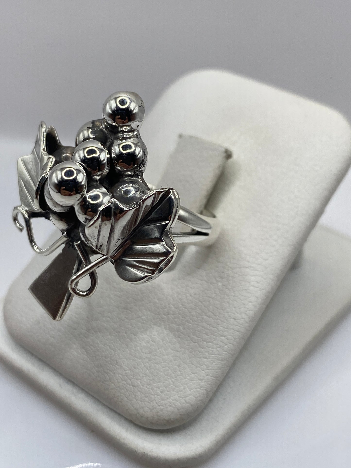 Anillo racimo en dedo, mostrando el diseño floral con esferas pulidas a espejo