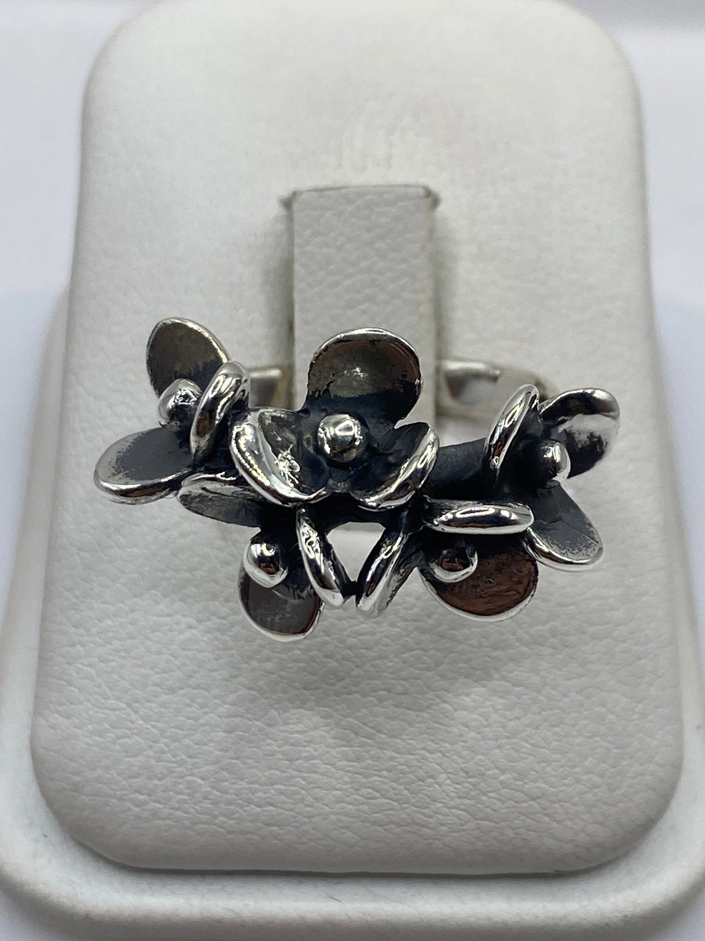 Anillo de plata con flores escultóricas fundidas, vista frontal en estuche blanco