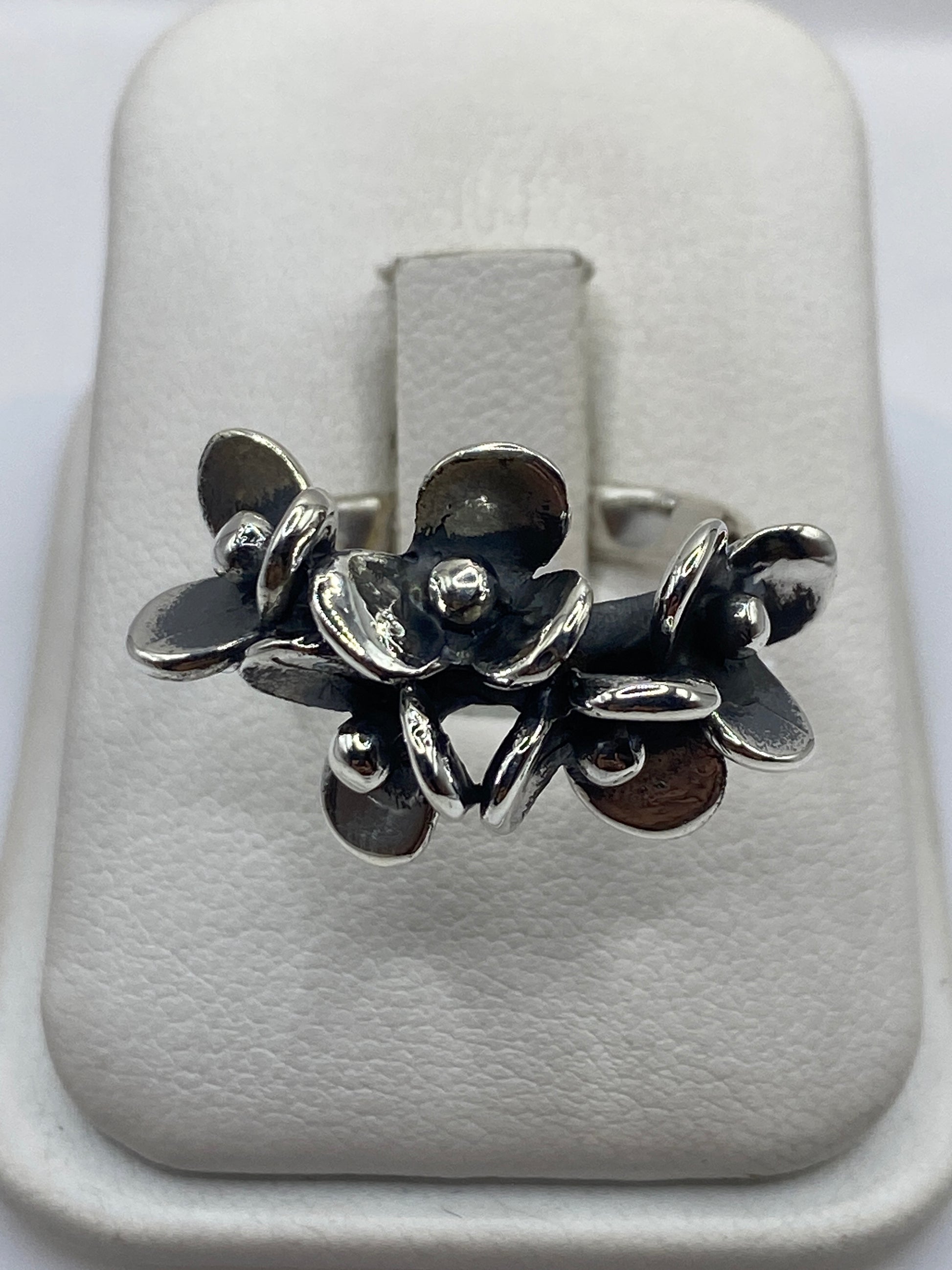 Anillo de plata con flores escultóricas fundidas, vista frontal en estuche blanco