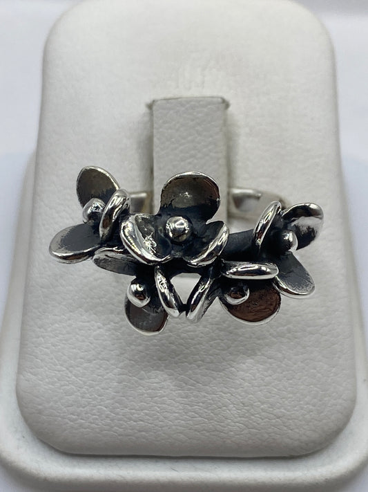 Anillo de plata con flores escultóricas fundidas, vista frontal en estuche blanco