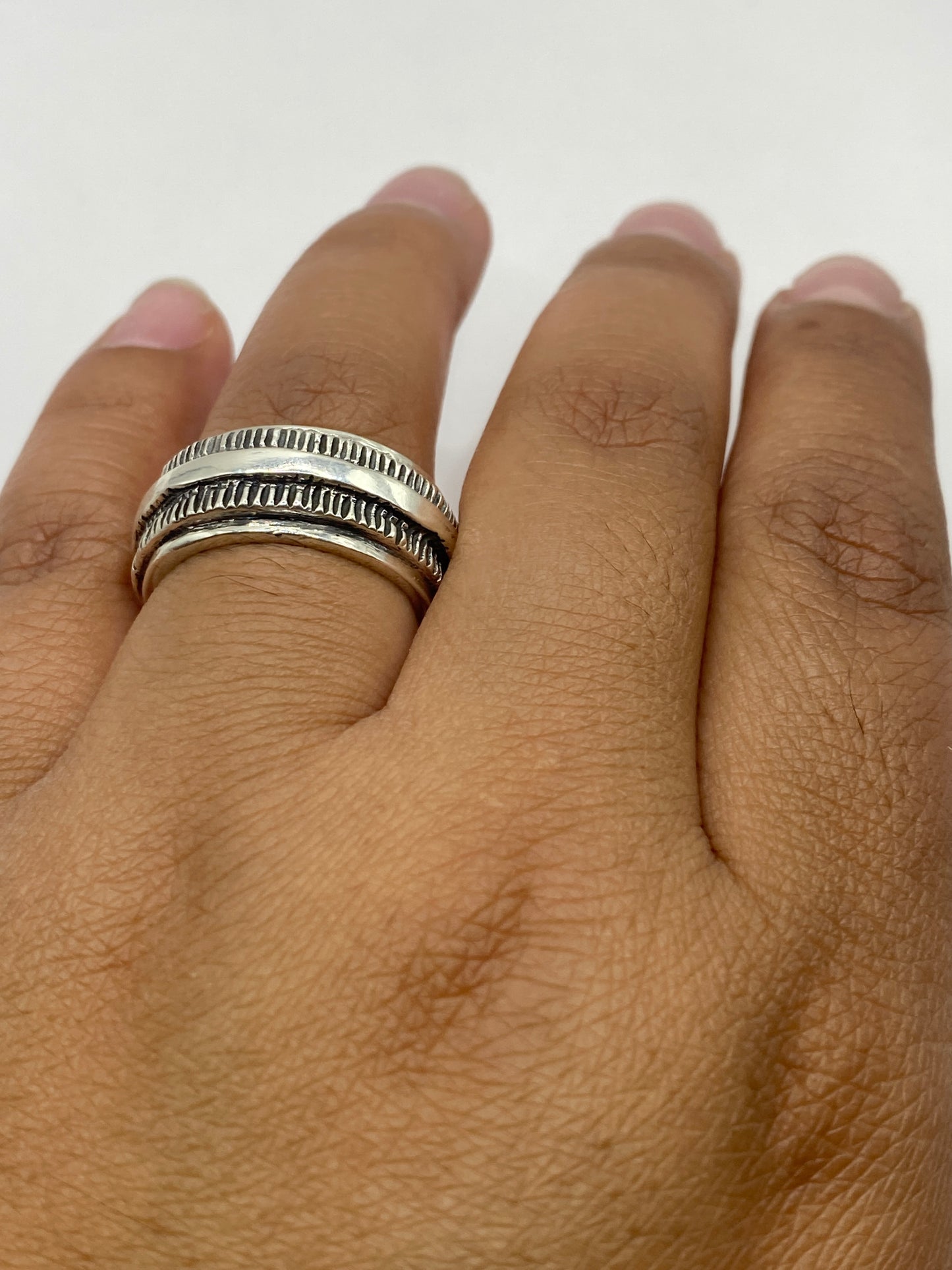 Anillo de plata sustancial sobre fondo gris, vista de perfil