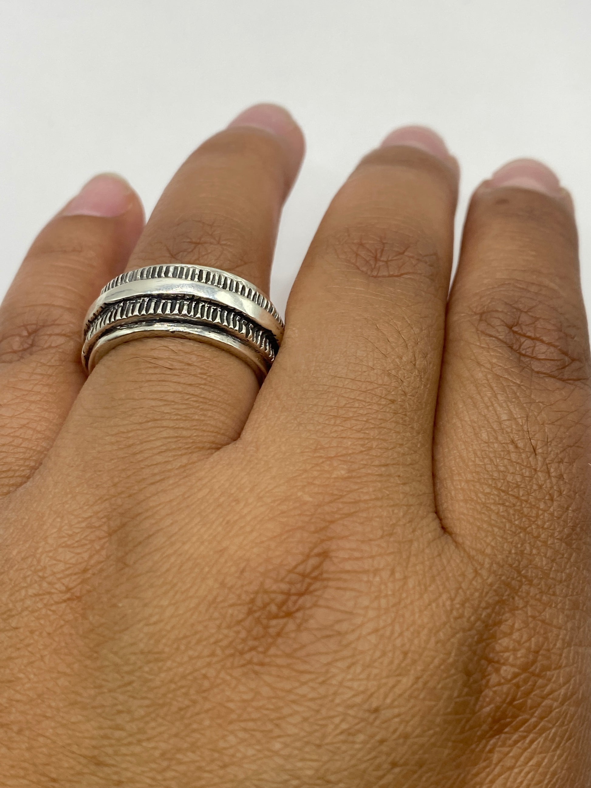 Anillo de plata sustancial sobre fondo gris, vista de perfil