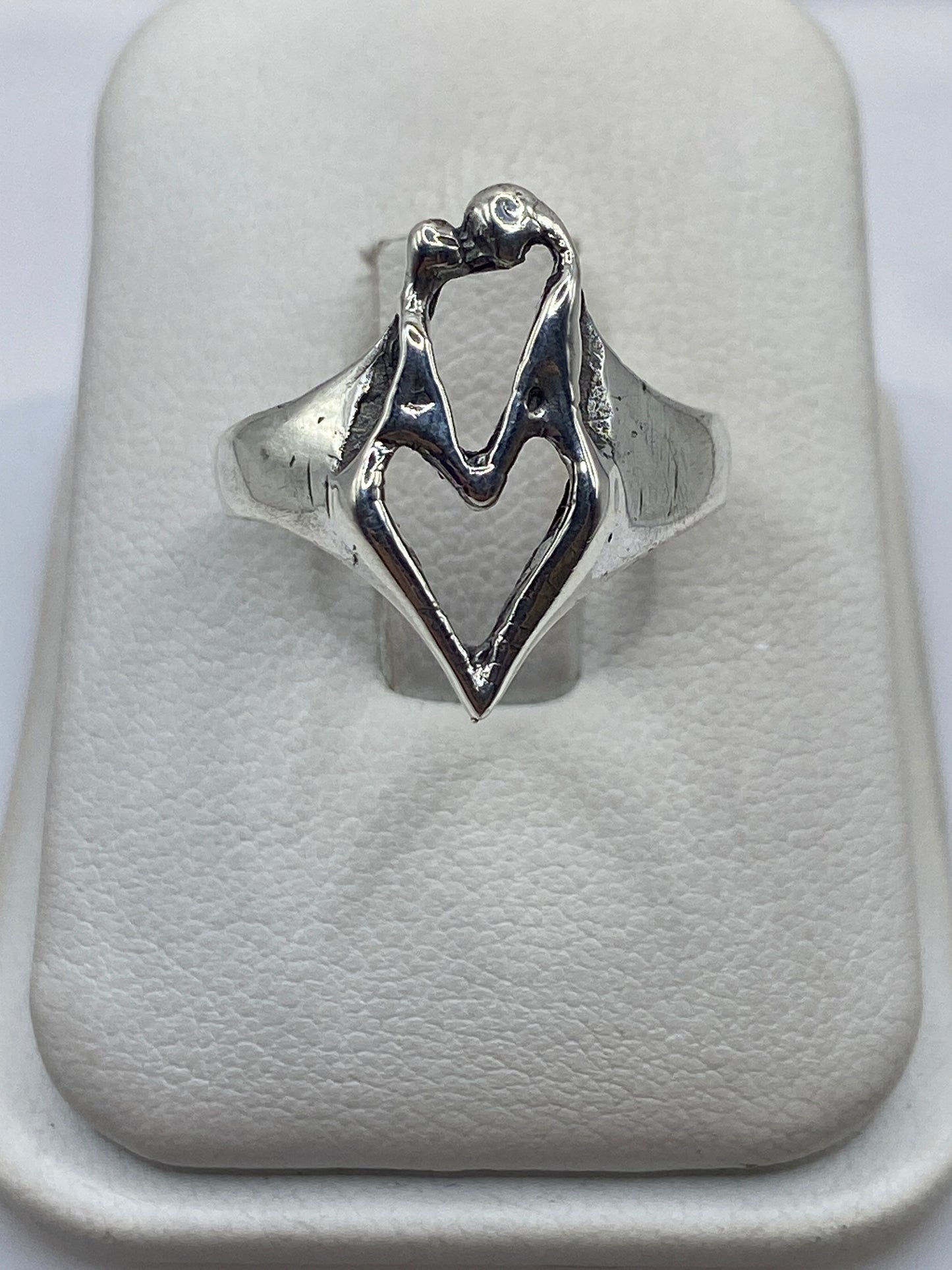 Anillo de plata con manos entrelazadas, diseño escultural brillante sobre fondo blanco