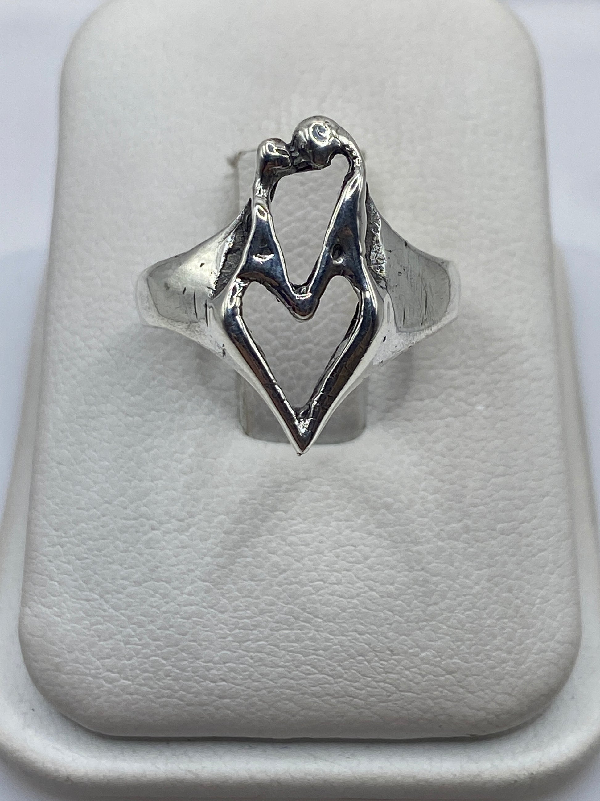 Anillo de plata con manos entrelazadas, diseño escultural brillante sobre fondo blanco