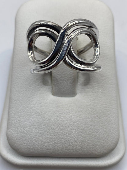 Anillo de plata con doble bucle geométrico entrelazado en la mano de una mujer