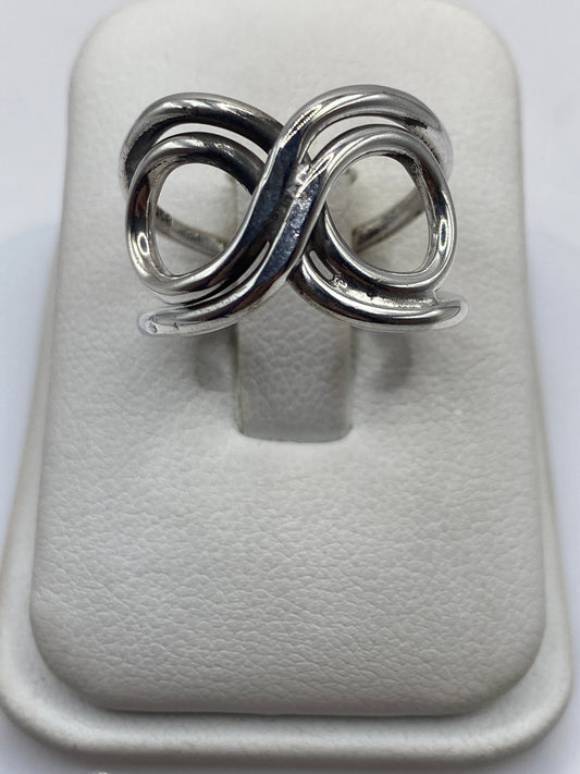 Anillo de plata con doble bucle geométrico entrelazado en la mano de una mujer