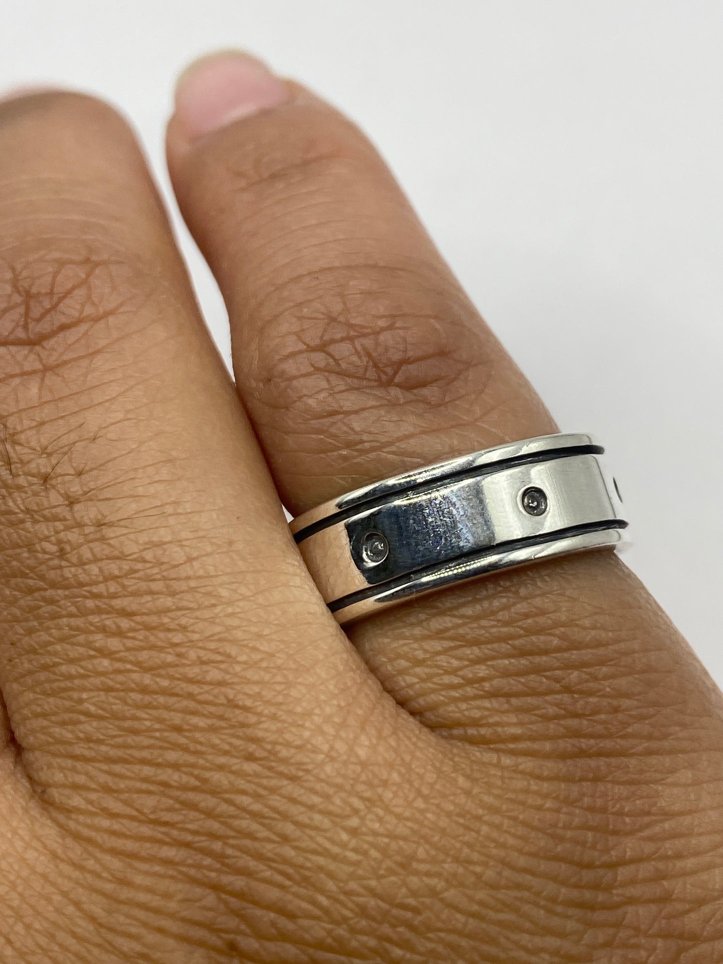 Anillo de plata sobre fondo blanco, perspectiva en escuadra revelando el grosor y los detalles