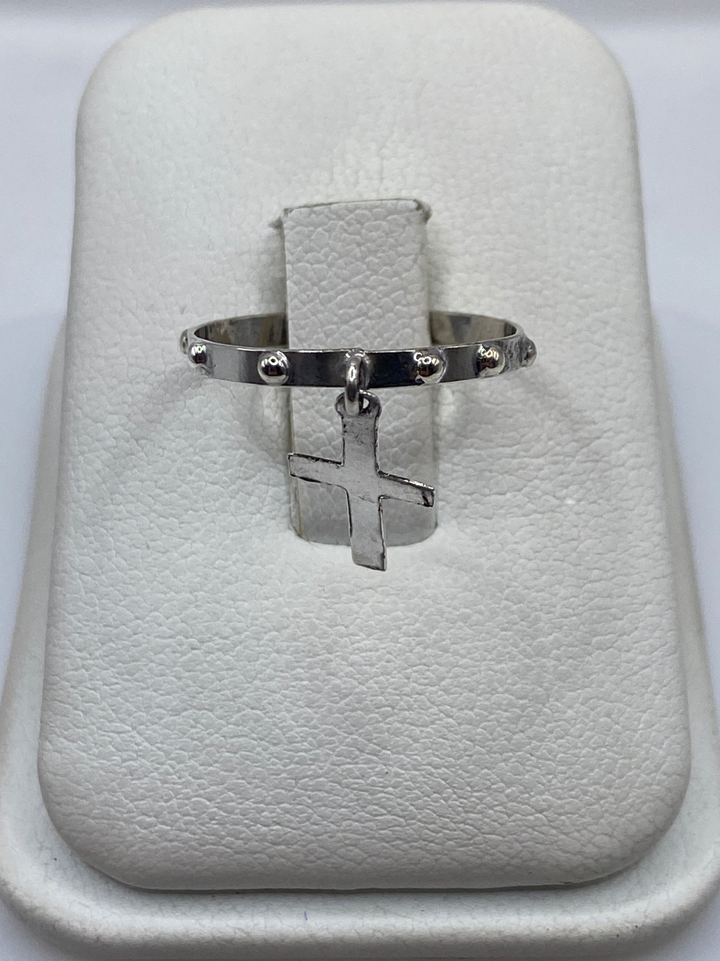 Anillo de plata .925 con cruz colgante minimalista en la mano de una persona