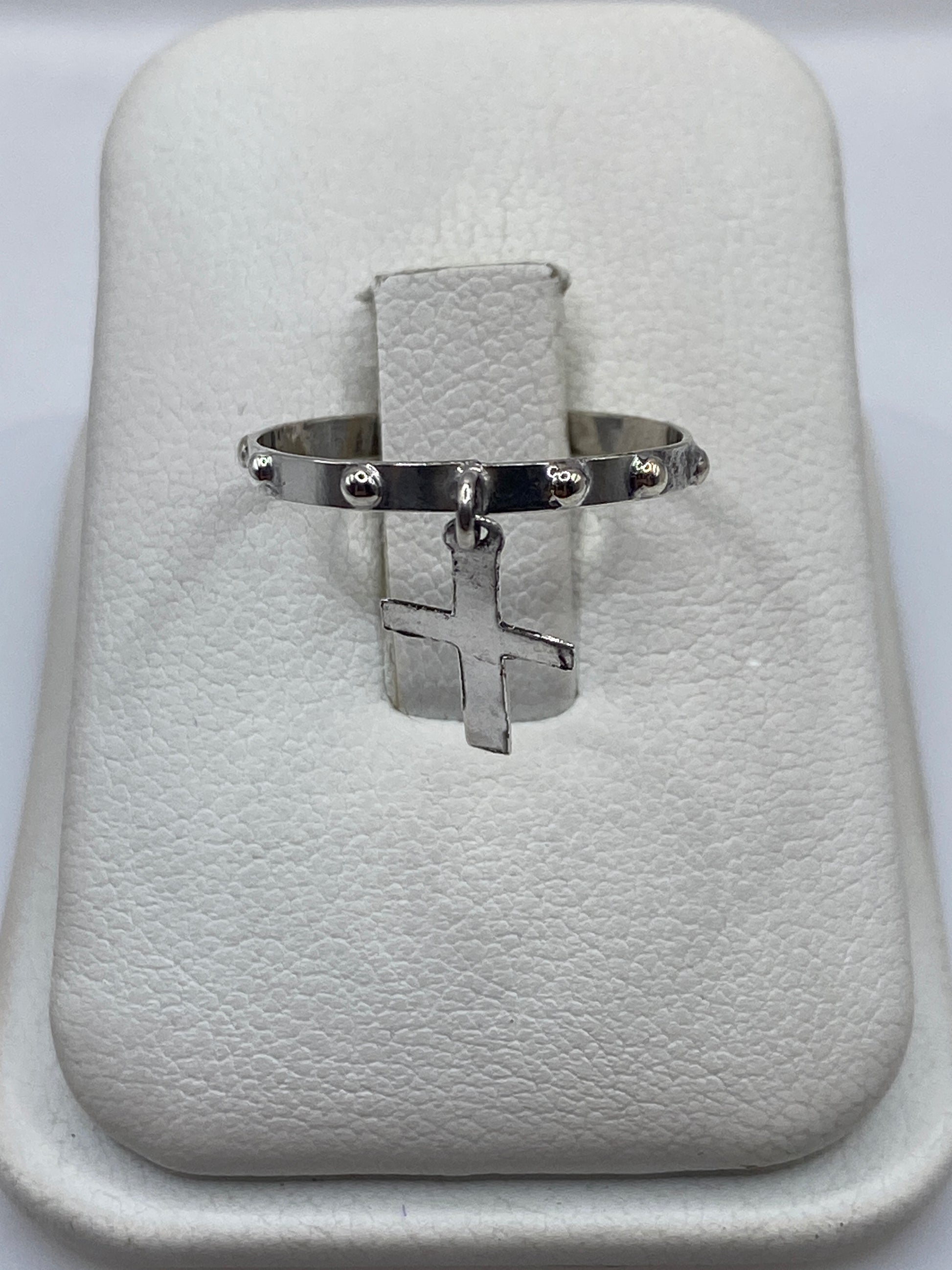 Anillo de plata .925 con cruz colgante minimalista en la mano de una persona