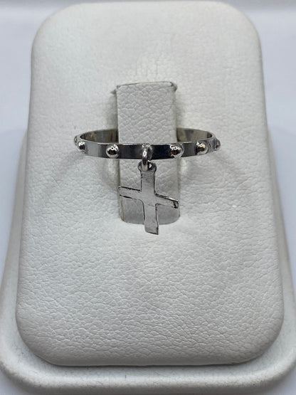 Anillo de plata .925 con cruz colgante minimalista en la mano de una persona