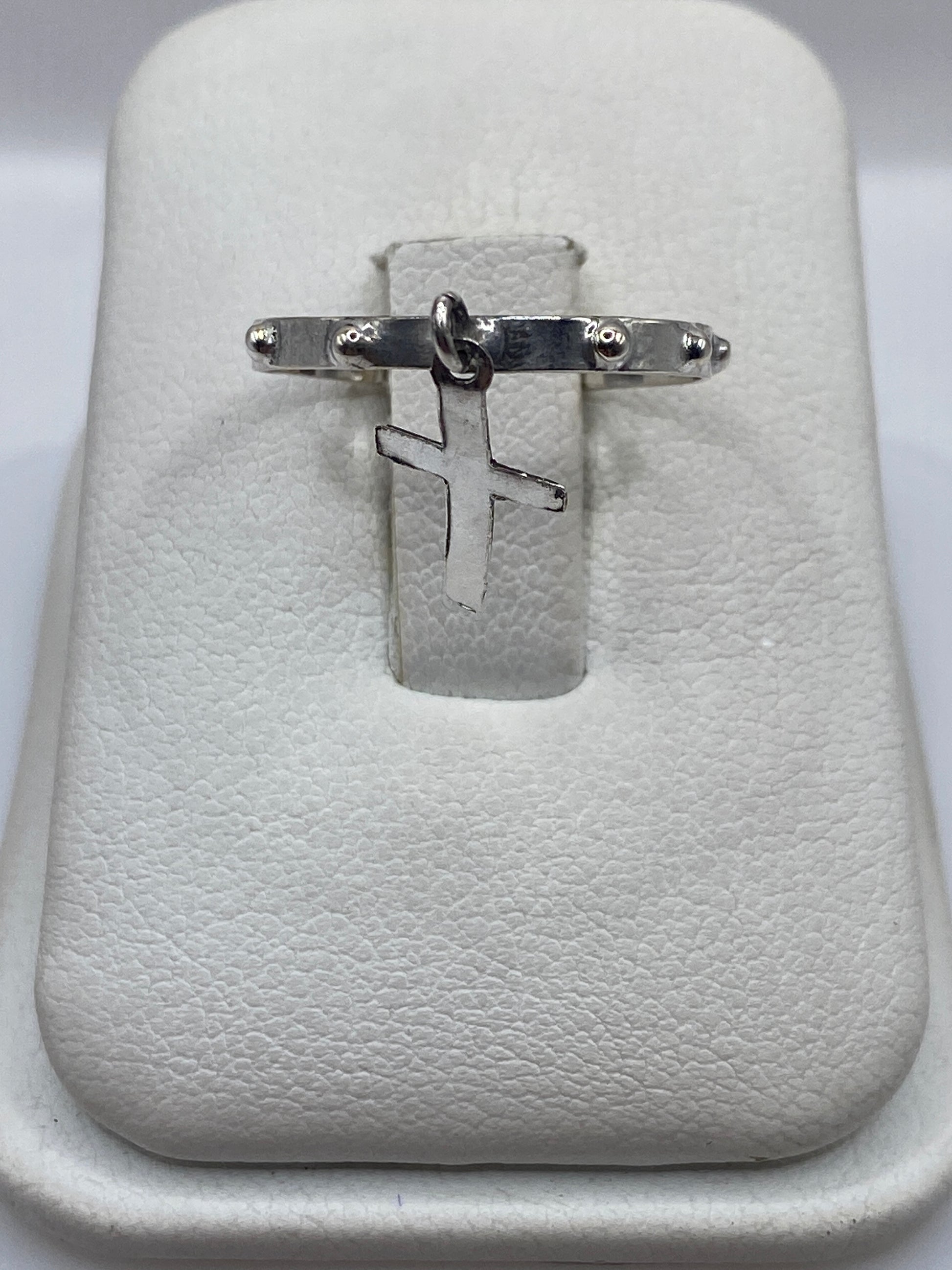 Anillo de plata .925 con cruz minimalista en la mano de un hombre