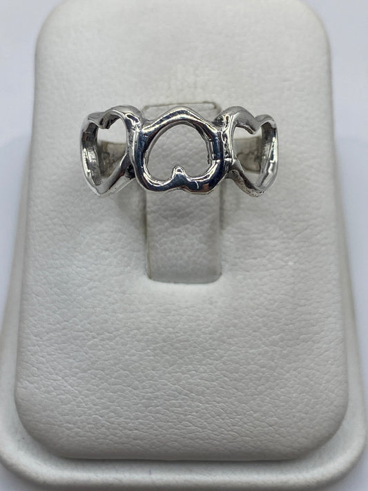Anillo de plata con tres corazones abiertos minimalistas en la mano de una mujer