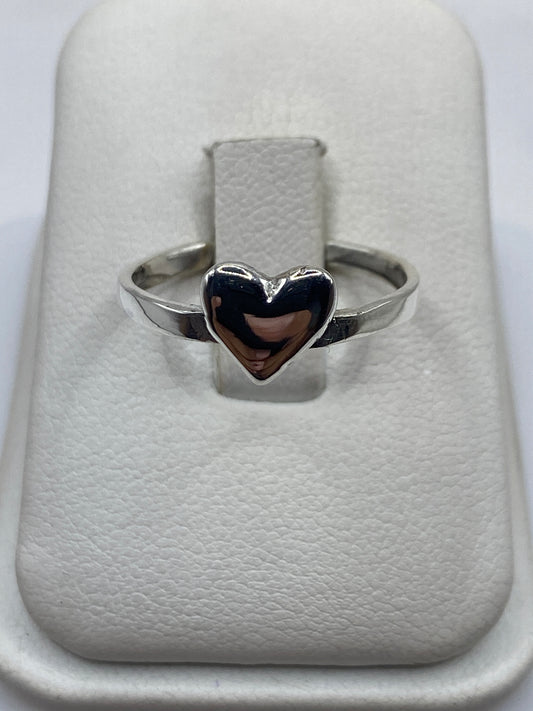 Anillo de plata con corazón pulido en mano de mujer, banda lisa minimalista