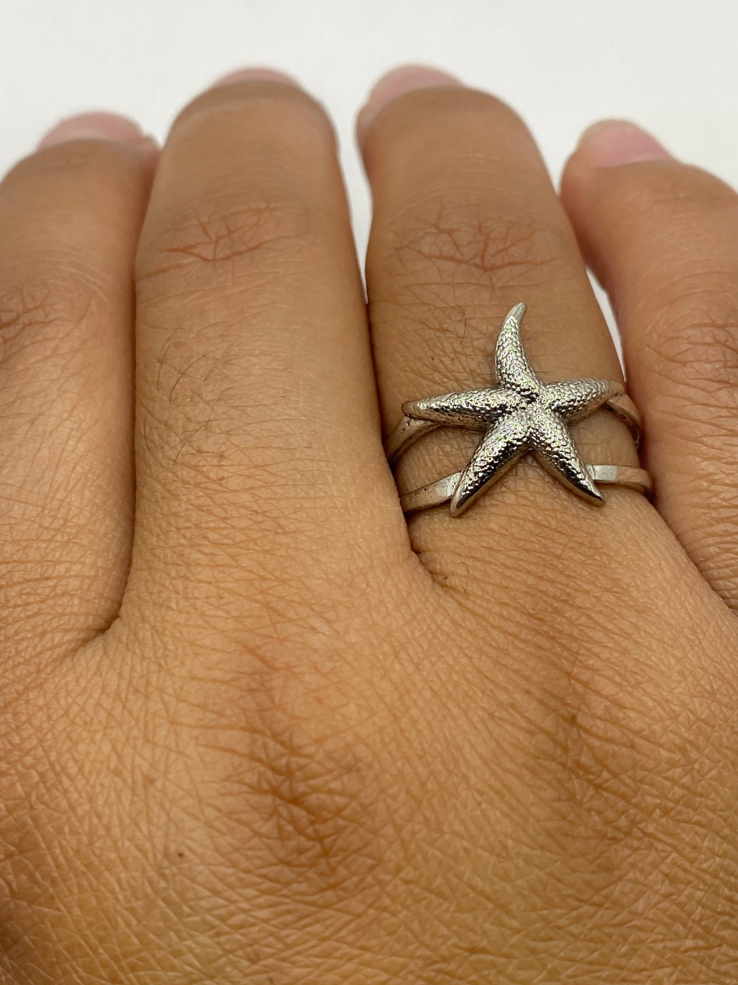 Anillo puesto en dedo mostrando la forma escultural en luz natural