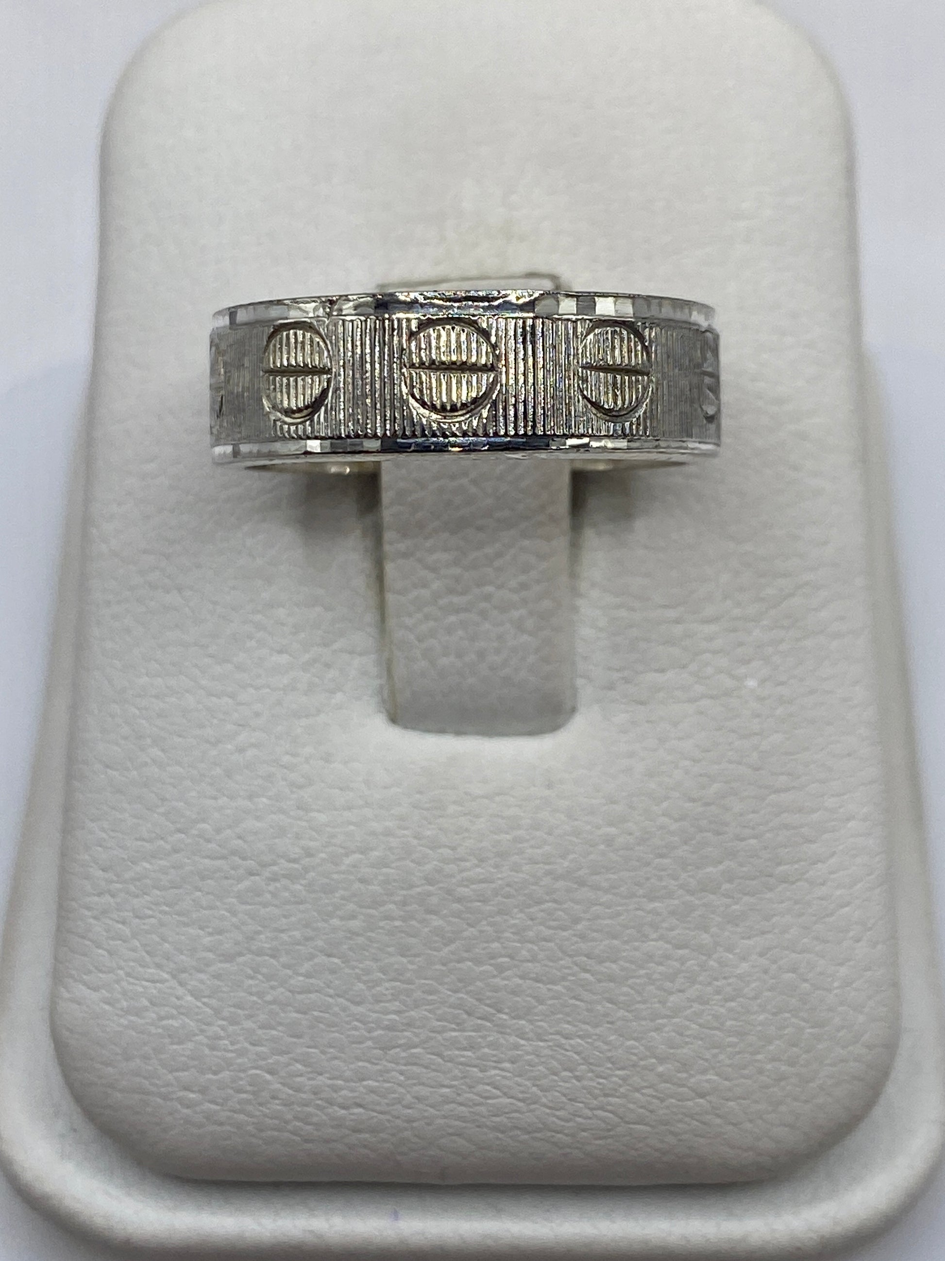 Anillo de plata banda texturizada con círculos y líneas en las manos de una persona
