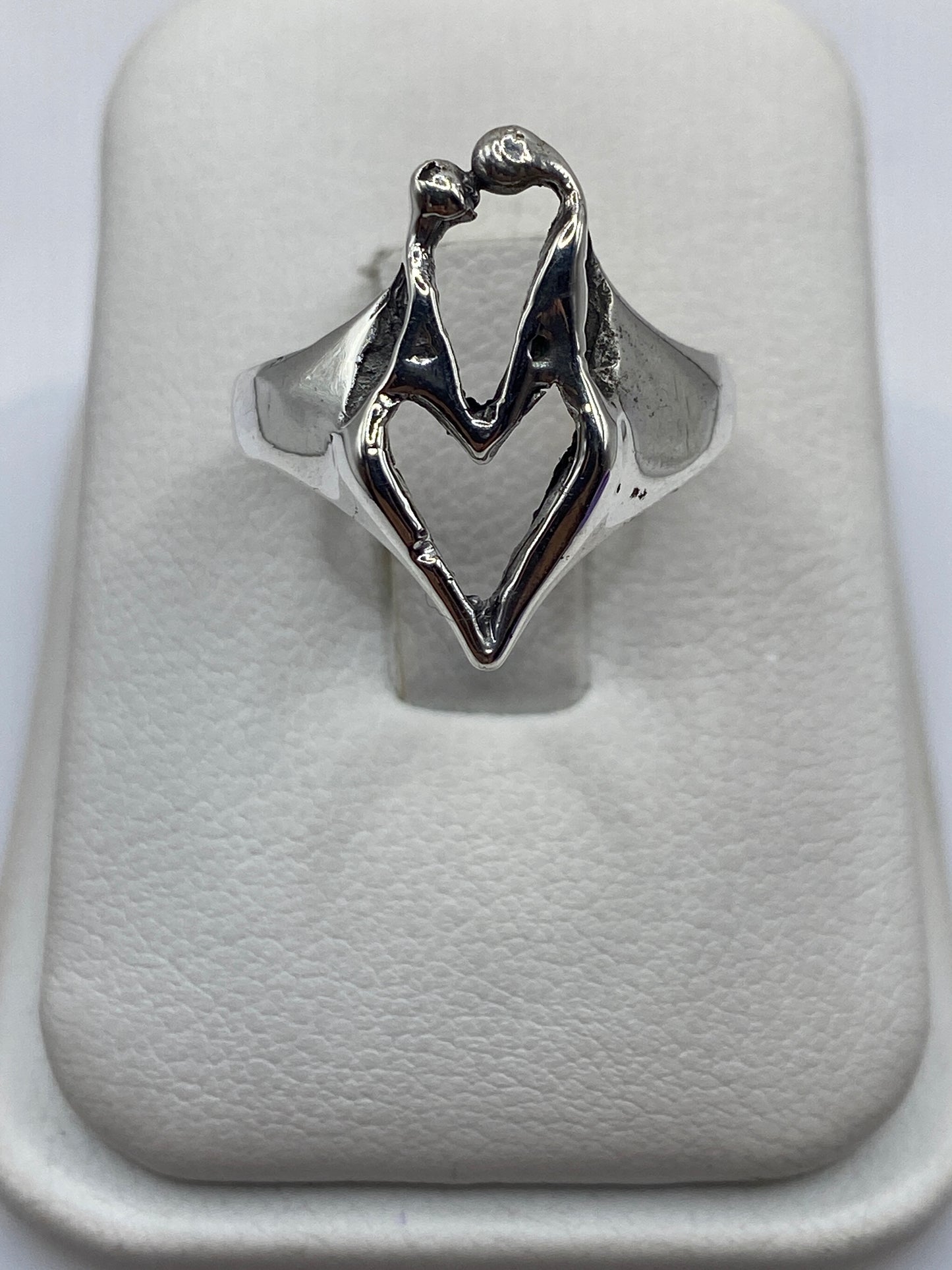 Anillo de plata con diseño de manos en abrazo sobre fondo blanco