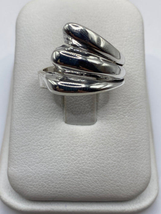 Anillo de plata con pétalos superpuestos en cascada, visto desde arriba sobre fondo blanco
