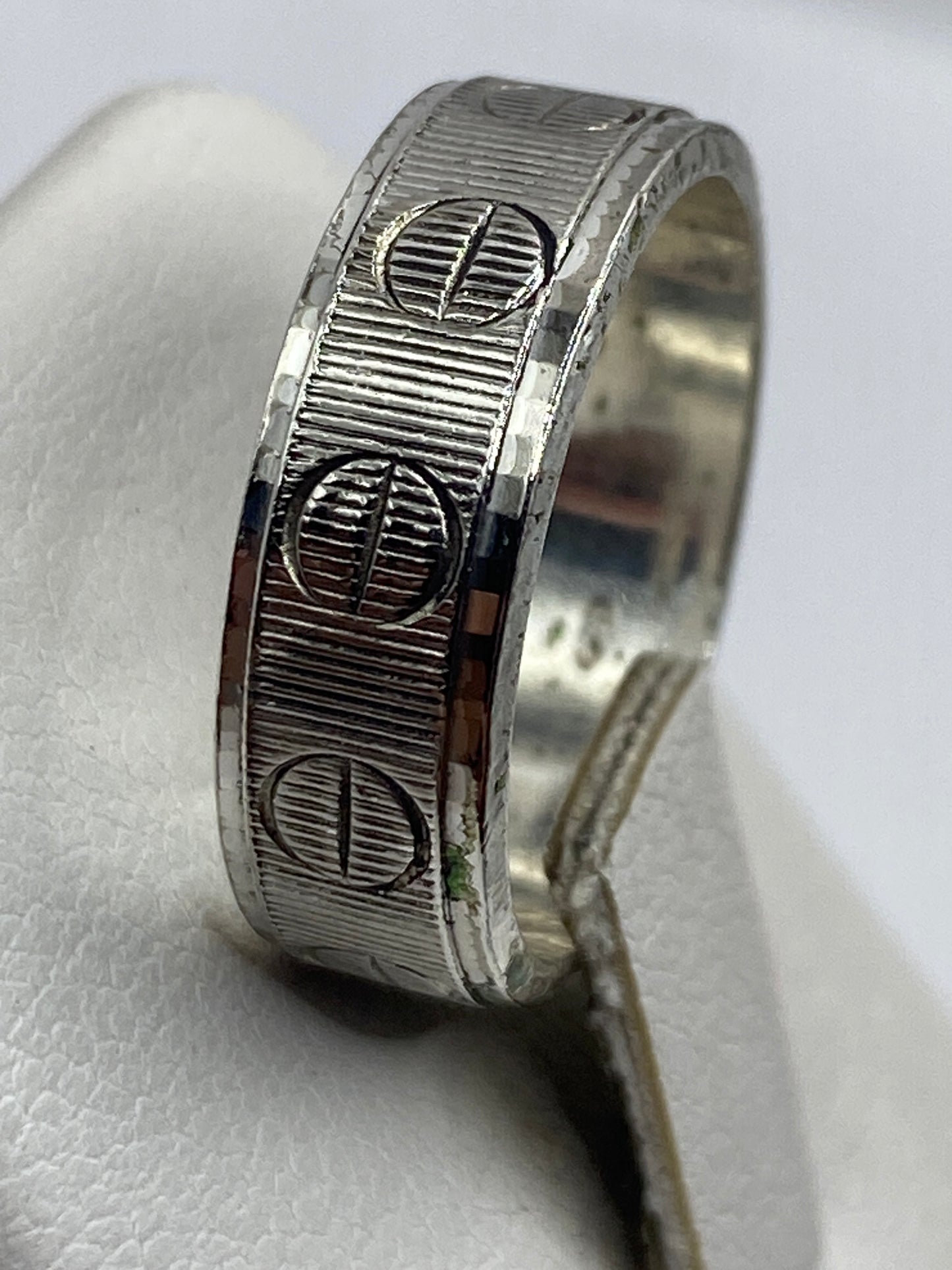 Detalle del anillo en la mano, luz frontal destacando la textura geométrica
