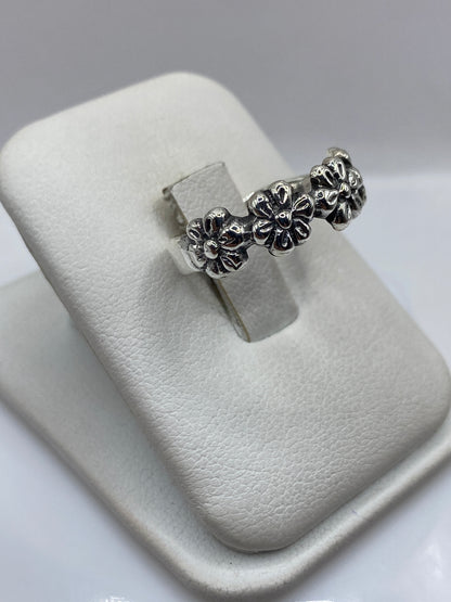 Vista frontal del anillo floral de plata artesanal en mano de mujer