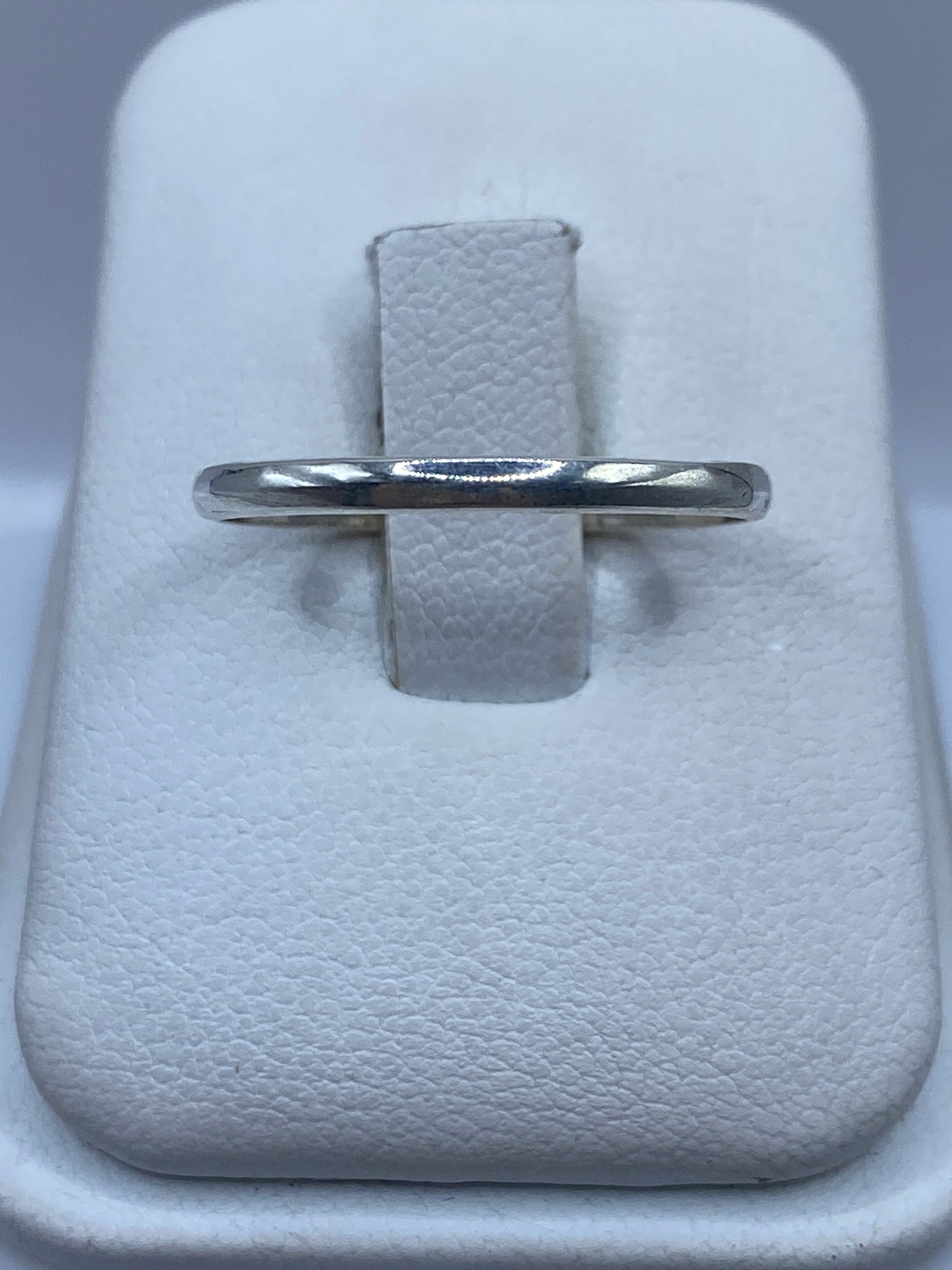 Anillo banda de plata pulida minimalista sobre fondo blanco